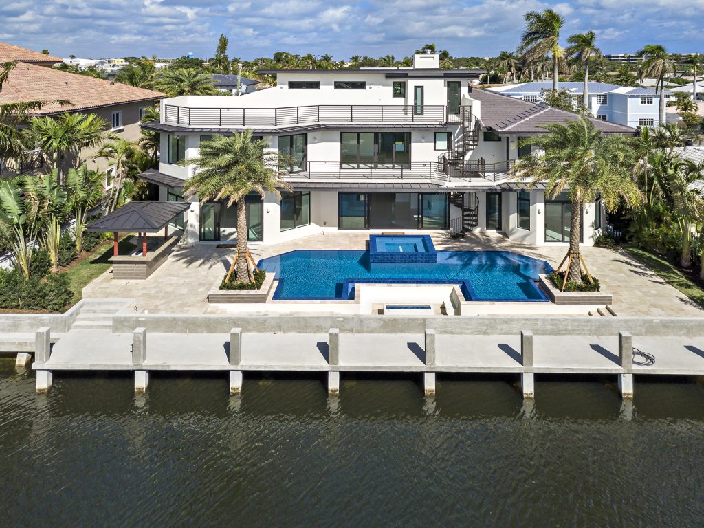 Waterfront home with walls of impact glass sliding doors facing the pool and canal
